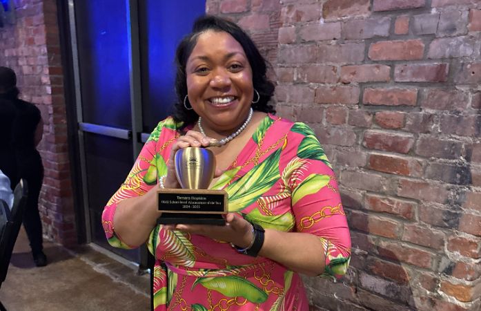  Dean Hopkins hold her award from the district