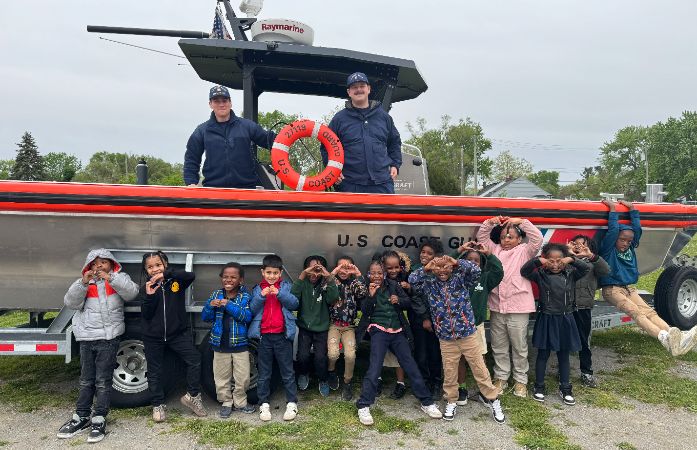  Students pose with Coast guard members and a boat on College and Career Day at Mann