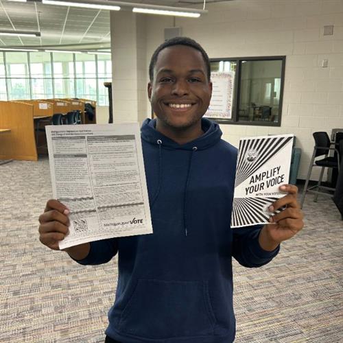 student holding voting application and literature