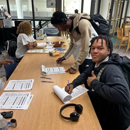 student sitting at table with thumbs up while completing voter application