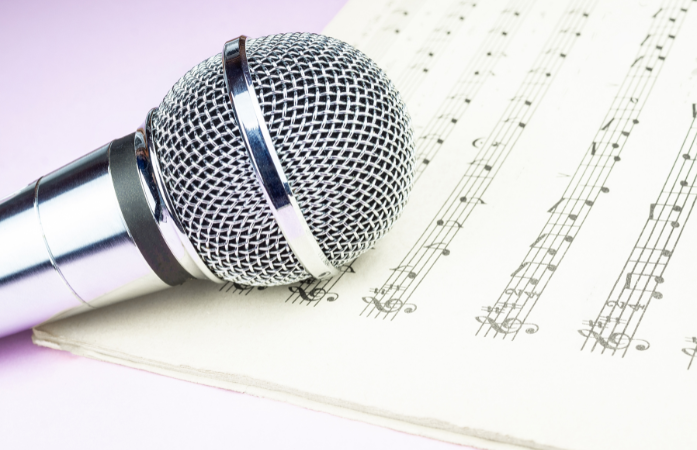  a silver microphone laying on sheet music