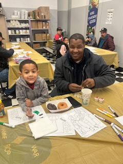 Father and son sitting at a cafeteria table with donuts and coloring sheets