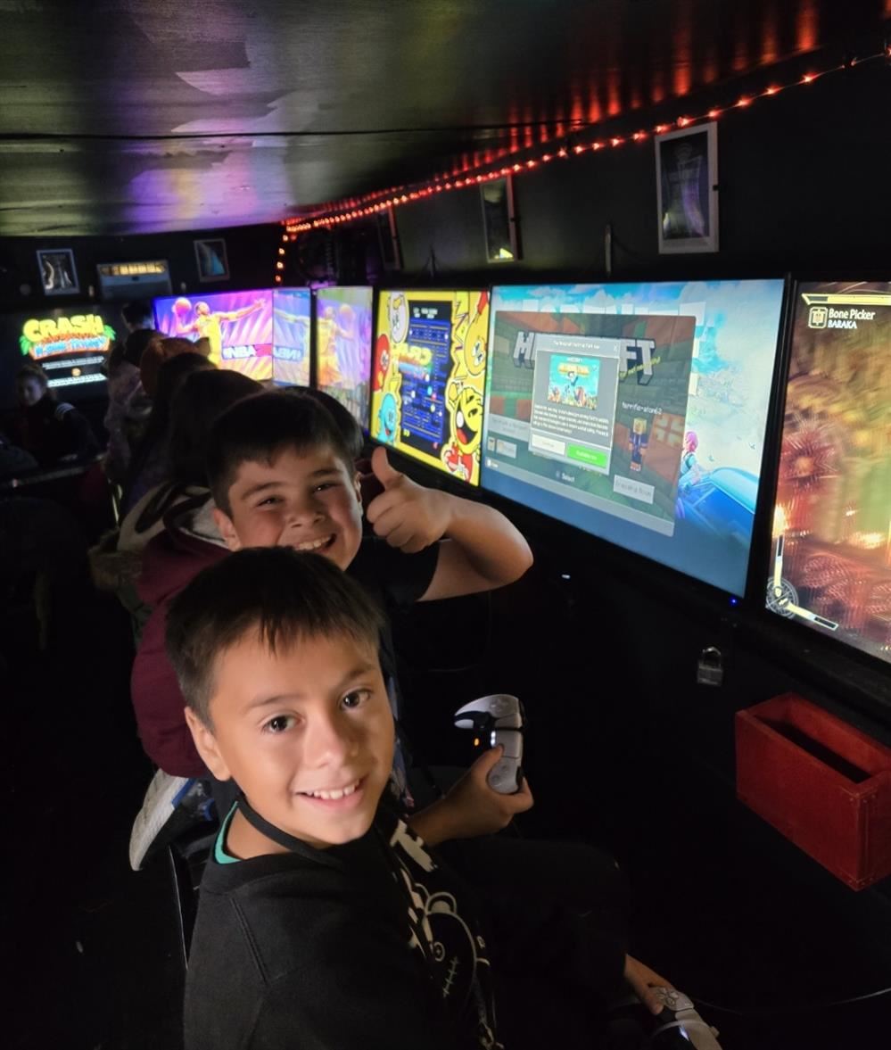 2 boys smiling with lots of tv's in the background