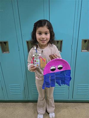 a girl standing holding 2 handmade toys