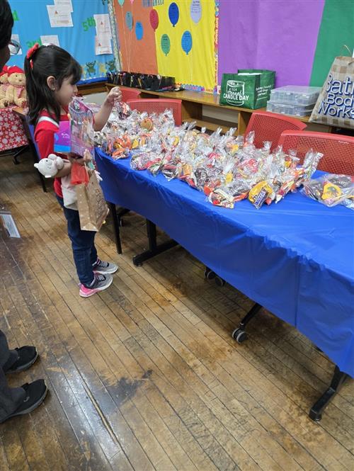 a girl standing at a table full of candy holding toys