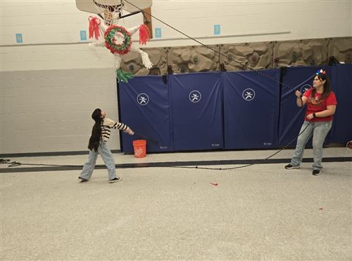 a kid looking up at a pinata and an adult holding a rope