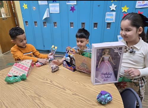 3 students standing at a table with toys