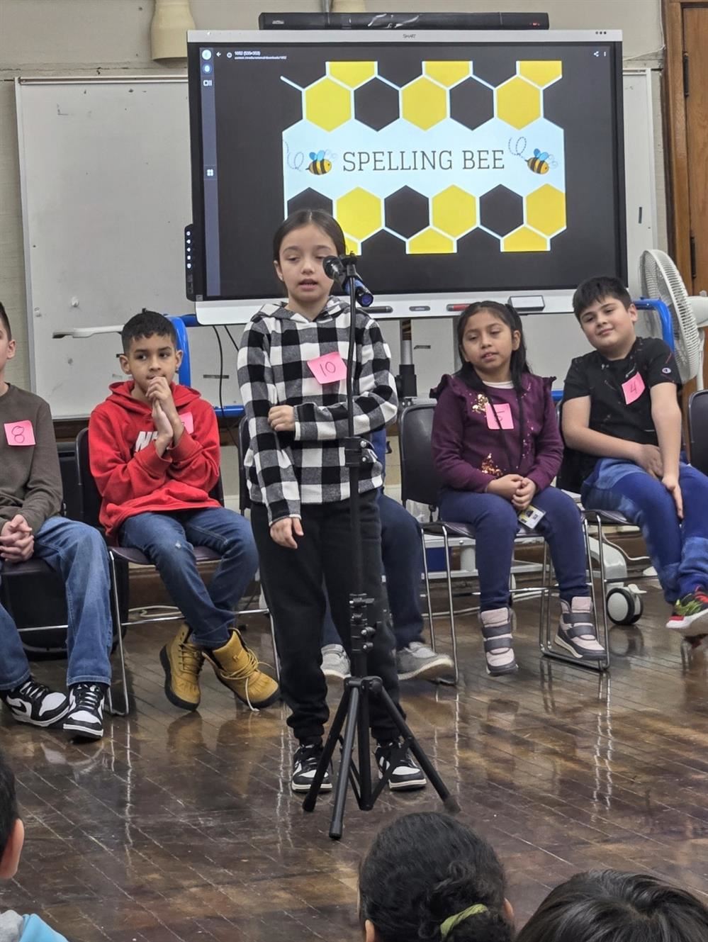  student standing at a microphone and students sitting in chairs