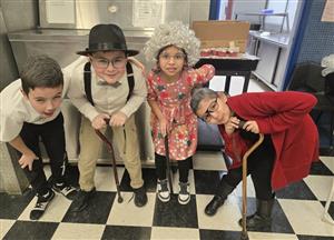  4 students hunched over dressed as elders