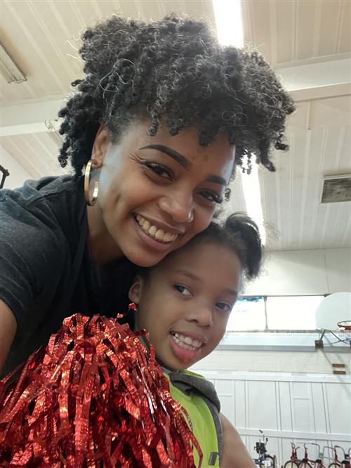 Student holding red pom pom with teacher at school Positive Behavior Intervention and Support pep rally