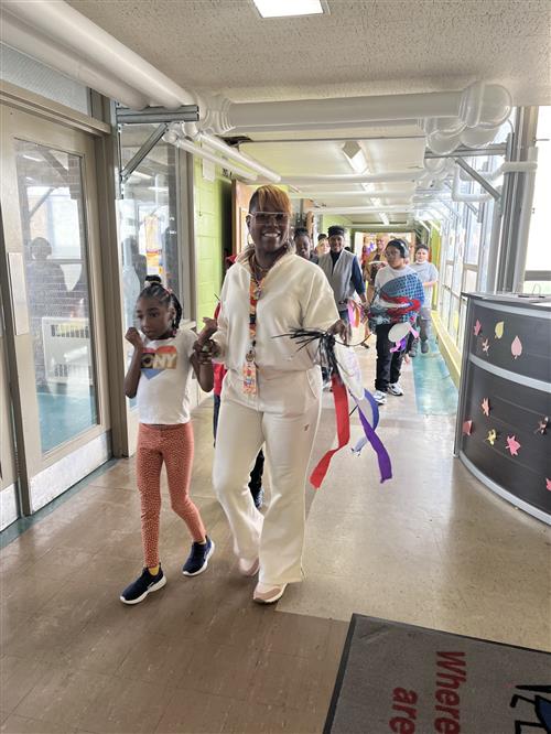 Teacher leads through school hallway for P.B.I.S. pep rally parade with students