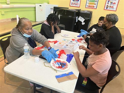 Students and staff working together making pom poms in the school cafteria
