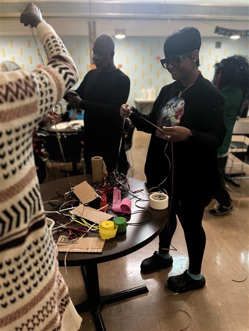 Teachers in school cafeteria making pom poms for pep rally