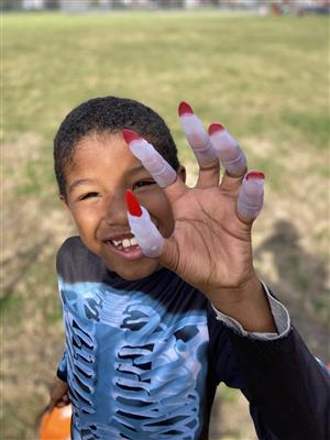 student smiling with witches fingers on