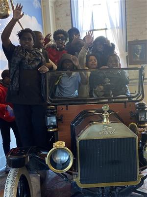 group of students sitting in model t car