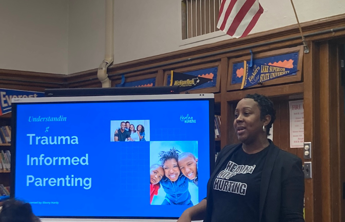  a presenter in front on screen reading trauma informed parenting