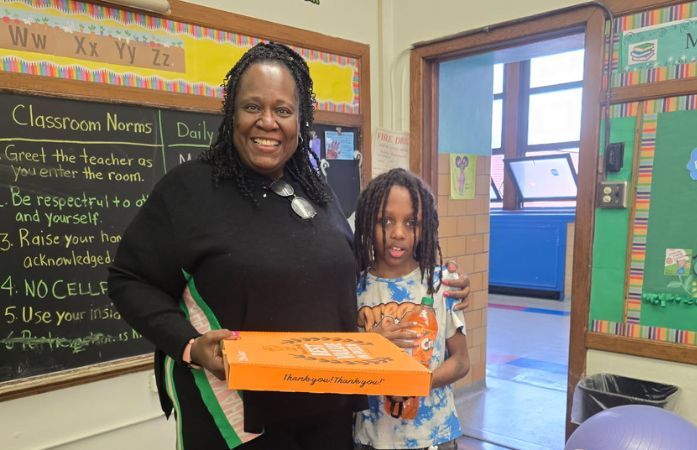  Tristen standing with Teacher Hurt-Matthews holding a pizza