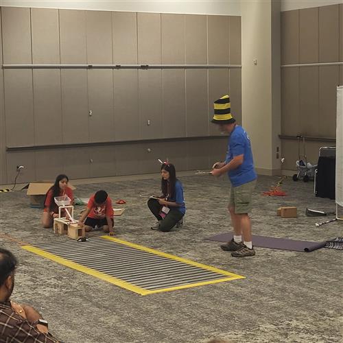 Students working to launch a catapult set with beanbags. Judge standing by. 