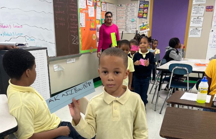  PreK students showing their handwritten names to middle school students
