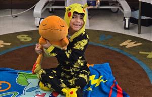 Student with stuffed animal in pajamas on blanket