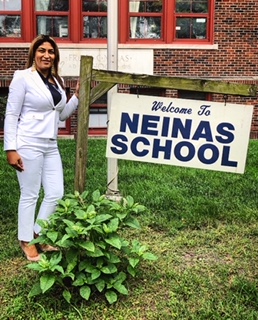 Principal Rendon standing next to a Welcome to Neinas School sign 