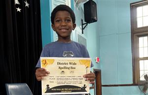 student standing with certificate for winning spelling bee