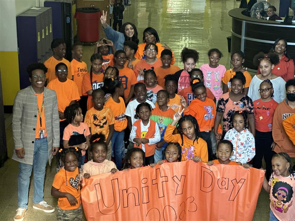  Students and staff standing with unity sign 