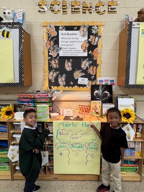  two kindergarten boys standing in front of a science station