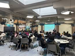  students sitting at tables for presentation