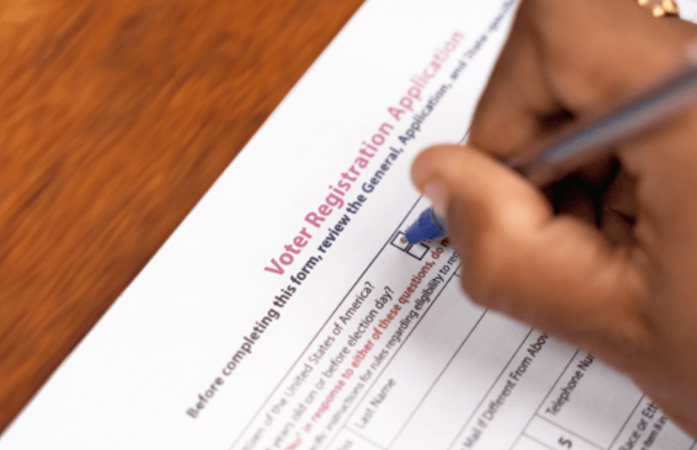 hand filling out a voter registration form