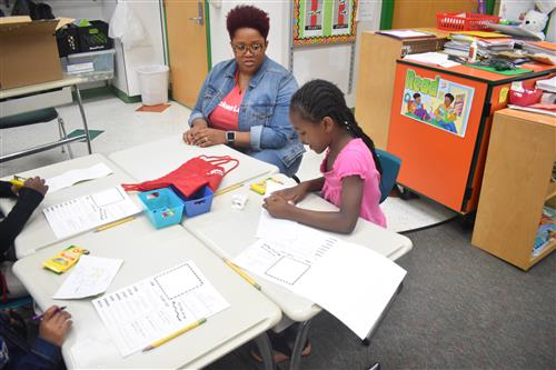 Volunteer sits at desk with first grade student 