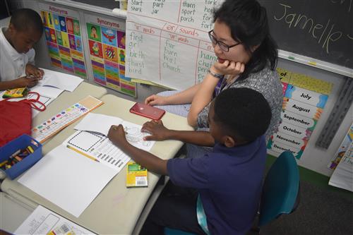 Tutormate volunteer sits at table with first grade student 