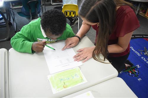 Volunteer from Tutormate work with first grade student on word search 