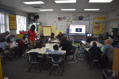 First grade teacher and Tutormate volunteers from Lear work with first grade students 