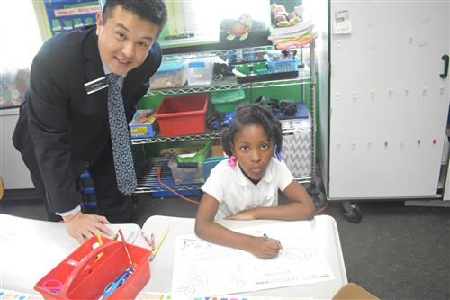 Comerica Bank volunteer stands by first grade student 