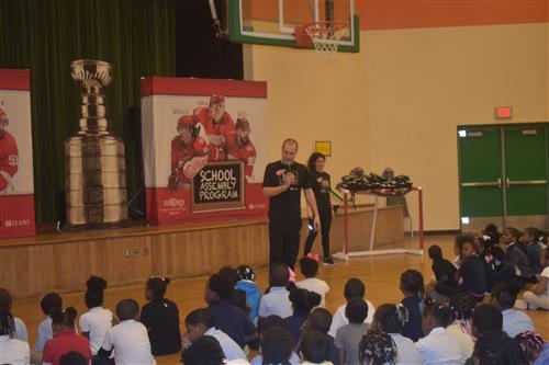 Students sitting on the floor while listening to representative from the Detroit Red Wings