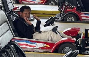  student sitting in a go-cart with hands up
