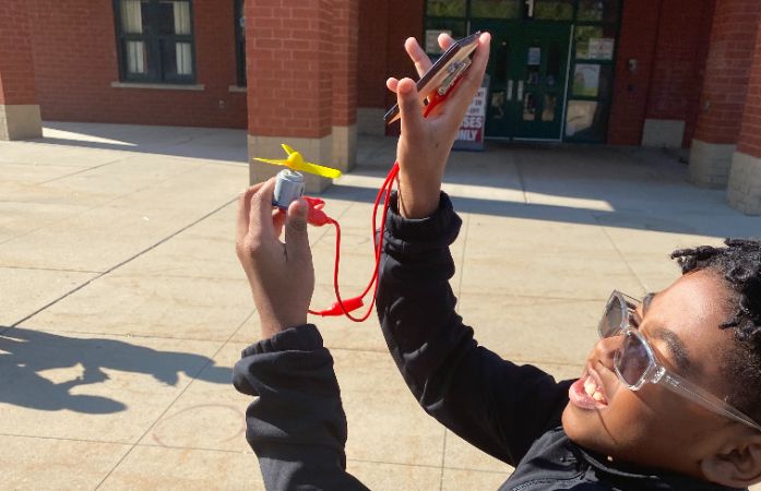  Student standing outside holding a fan and an energy source