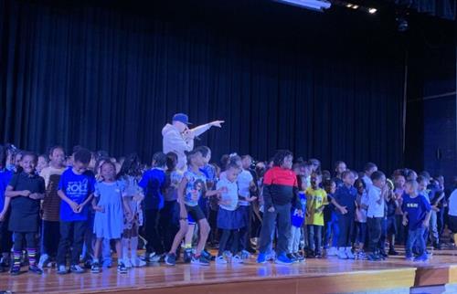 Thomas X performing onstage with students from Spain covering the stage