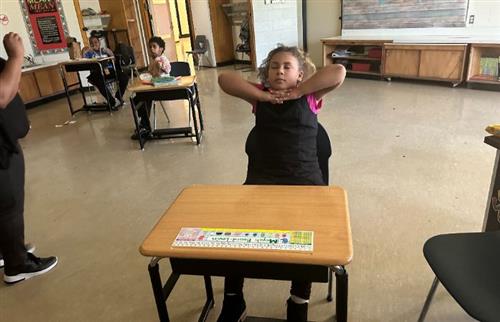  students sitting at her desk eyes closed calm classroom