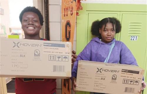  One male and one female student each holding a brown box.