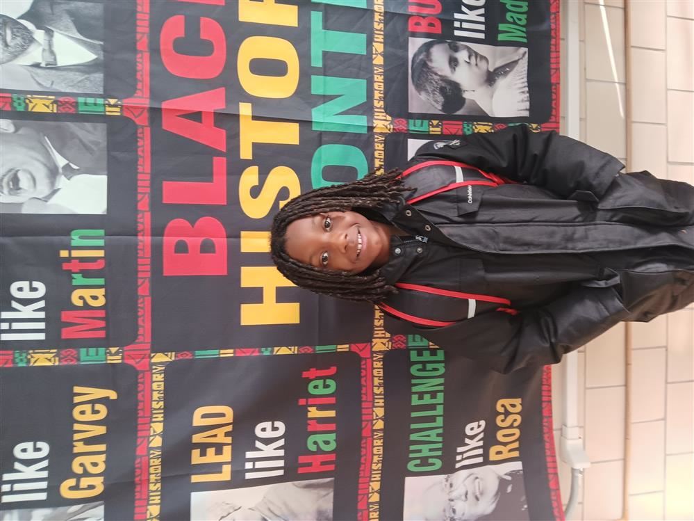  Little boy standing in front of a black history month banner.