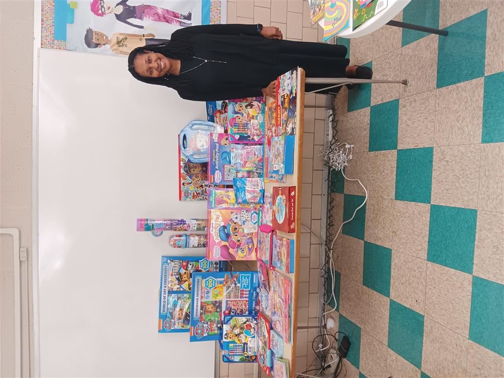  A woman stand next to a table with books.