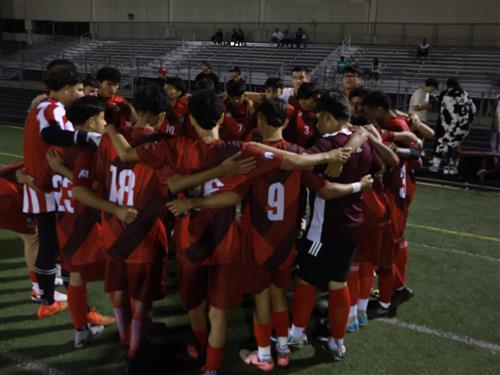 Boys Varsity Soccer team huddled up in a circle before a game.
