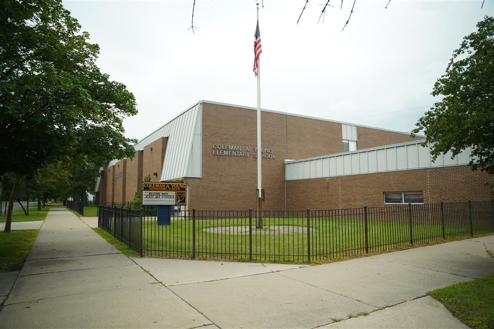 front of the brick school building, sign that says Coleman A Young Elementary and flag pole