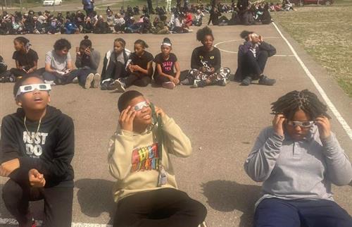 students looking up at the sun