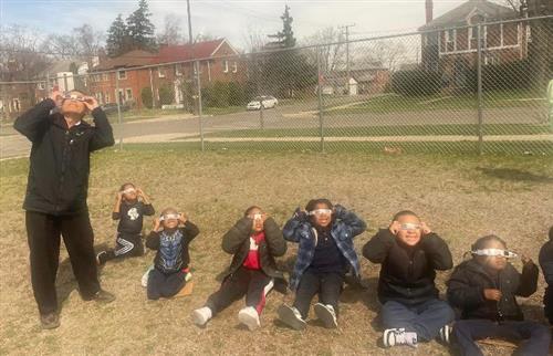 students looking up at the sun