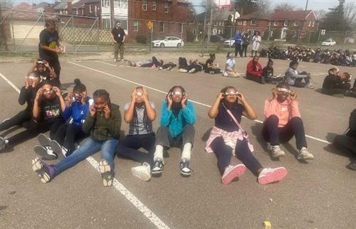 students looking up at the sun