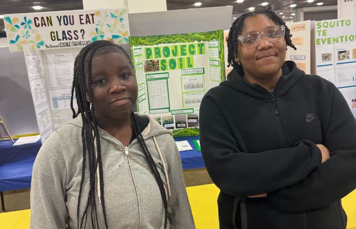  Two students standing before science posters.