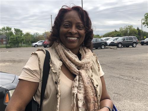 Teacher wearing a light top with a scarf smiling.